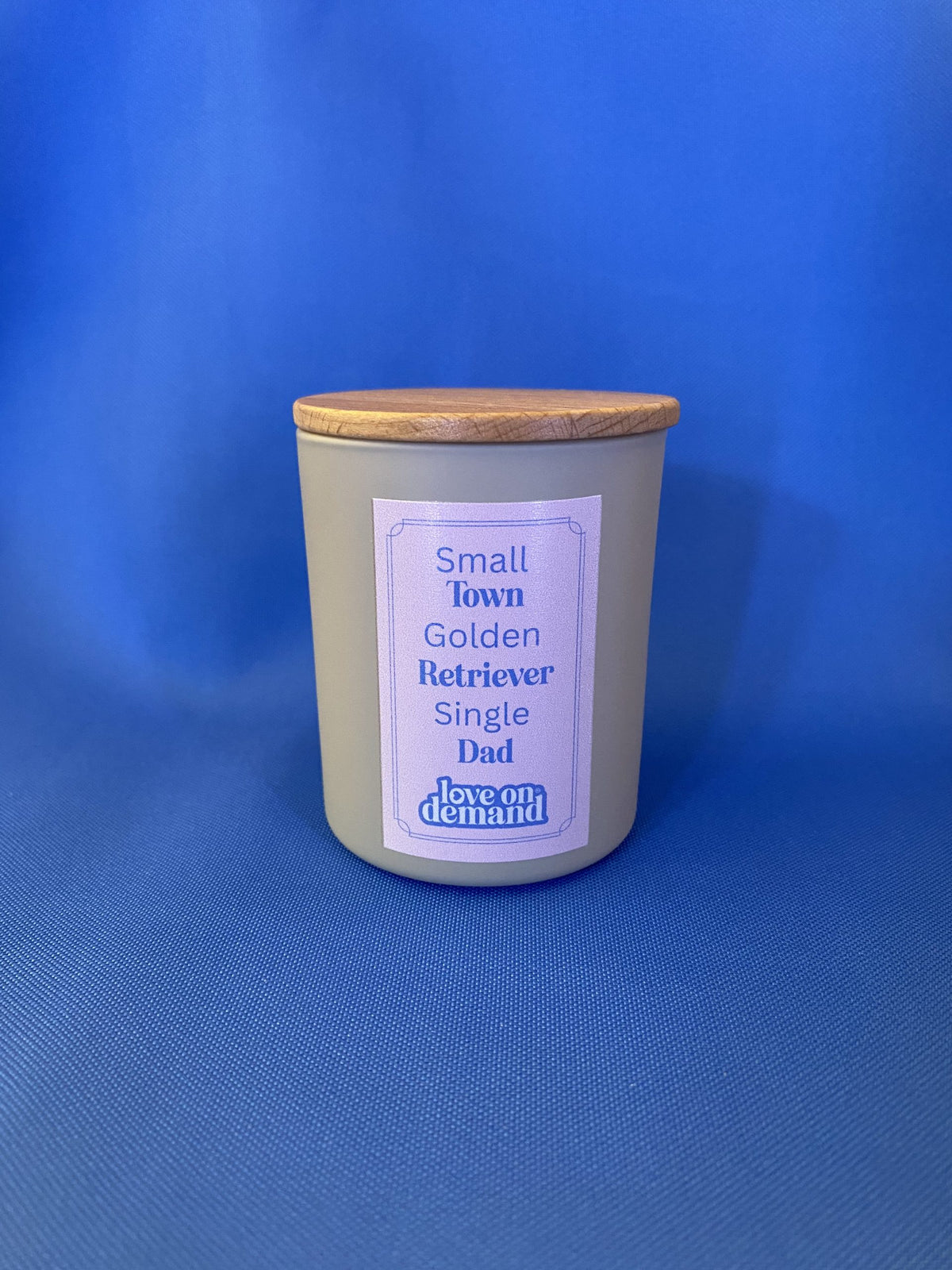Candle jar with a wooden lid and label on a blue background